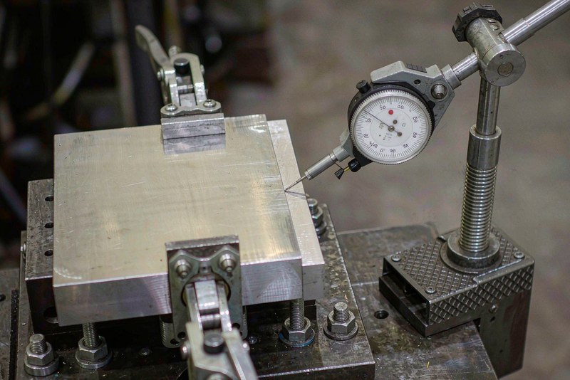 Machined plate clamped on a fixture with a dial indicator contacting the bore edge