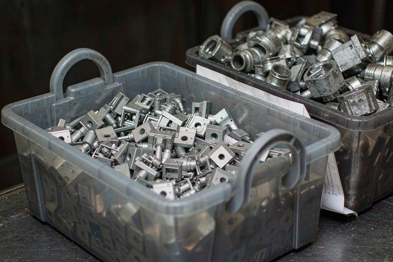Plastic bins of finished machined fittings waiting at a workbench for inspection