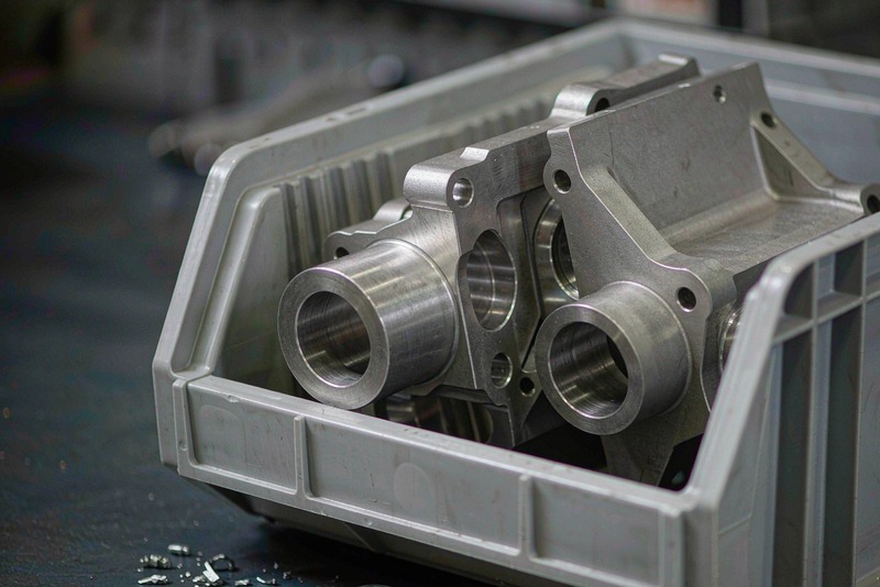 Batch of finished machined aluminum housings and brackets in a workshop bin