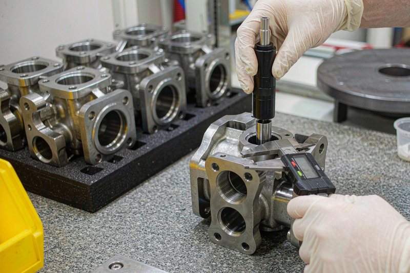 Thread plug gauge and caliper used to check a machined stainless steel housing