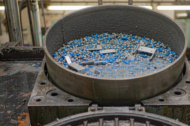 Vibratory finishing bowl running aluminum brackets through ceramic deburring media