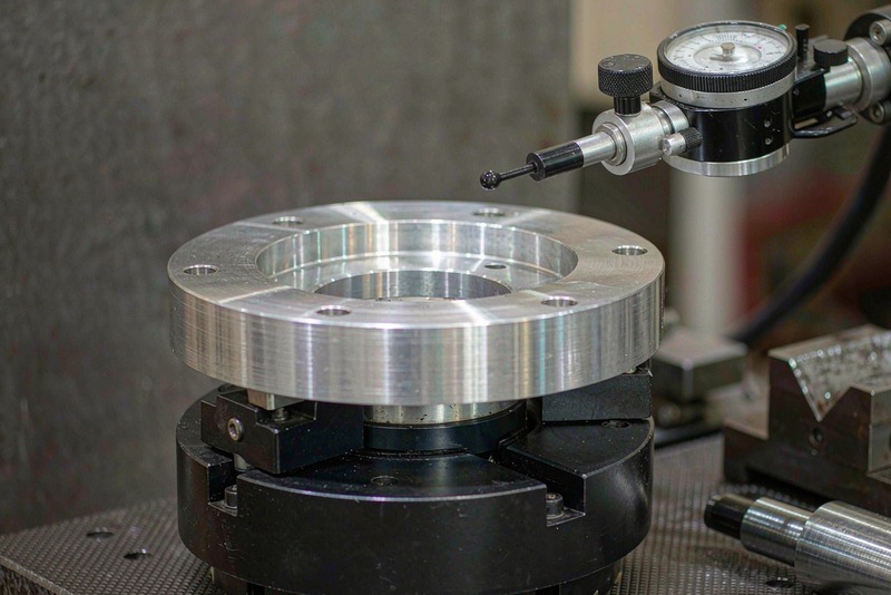Dial test indicator sweeping the face of a circular aluminum flange clamped on a rotary table