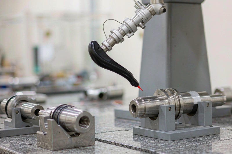 CMM touch probe measuring the cylindrical surface of a machined shaft held in a fixture