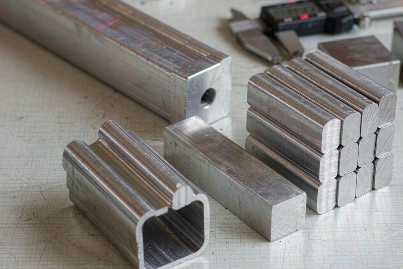 Sawn aluminum bar ends and square blanks stacked on a workshop bench