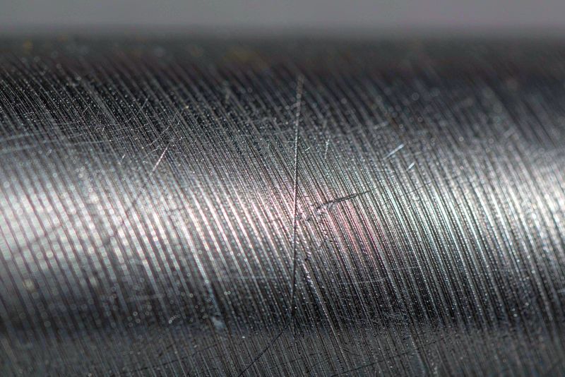 Close-up of a turned steel surface showing fine feed marks and one deep scratch