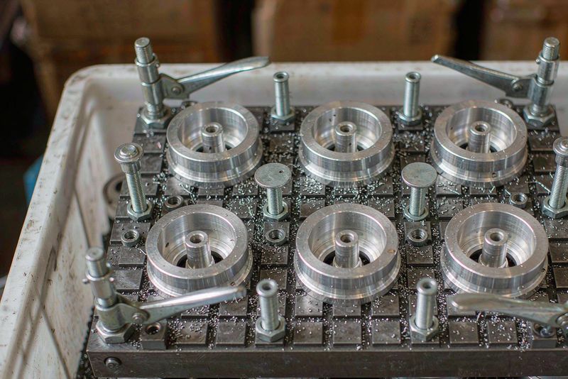Fixture plate with locating pins and toggle clamps holding six aluminum housings for batch milling