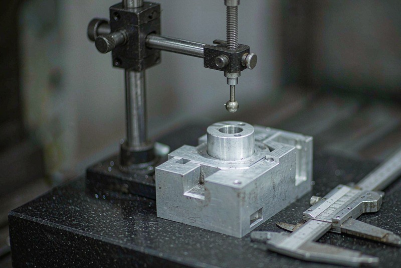 Aluminum housing on a granite plate while a dial indicator checks the top face