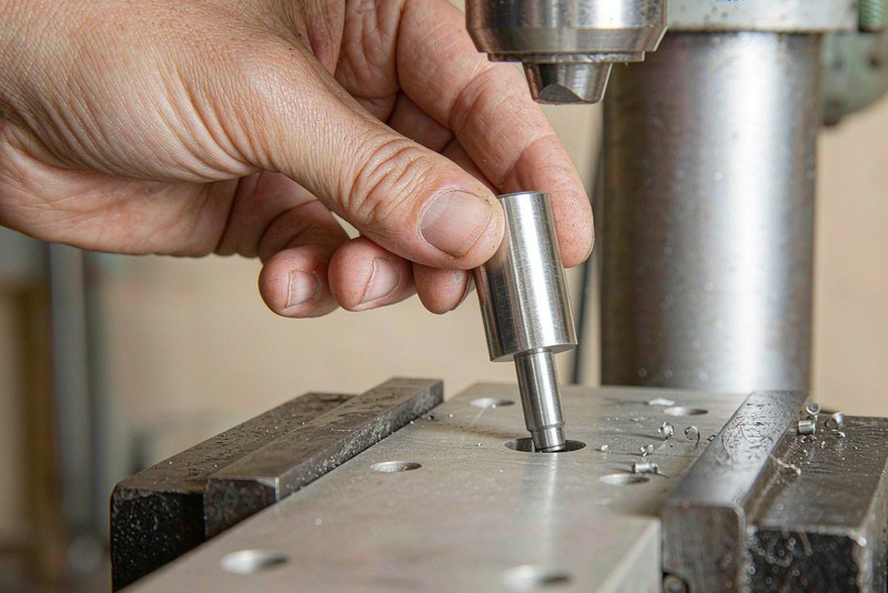 Plug gauge being inserted into a reamed hole in an aluminum plate