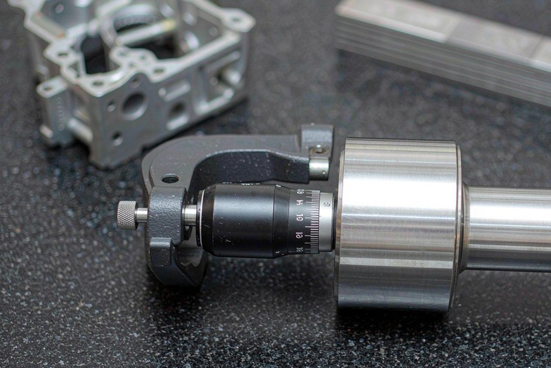 Outside micrometer measuring the turned diameter of a stainless steel stepped shaft