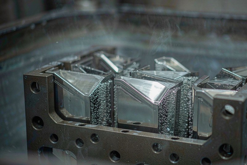 Stainless steel machined parts clamped on a jig inside an electropolishing tank