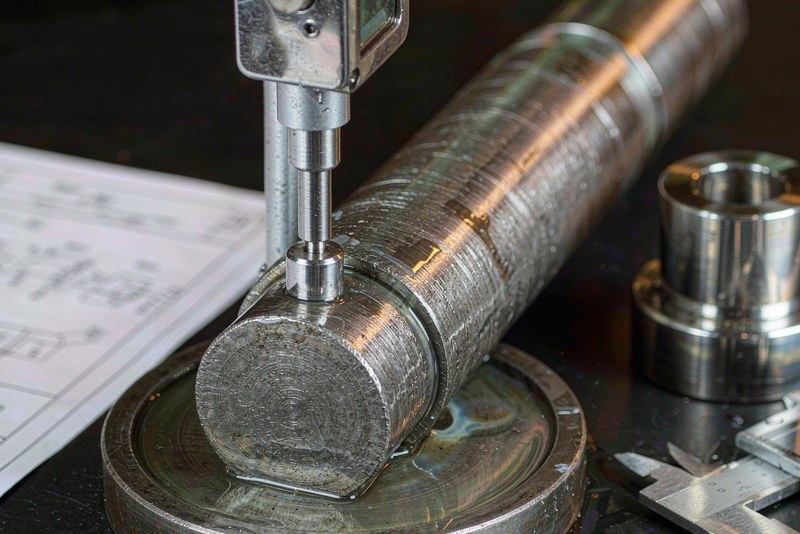 Micrometer measuring the turned journal of a stepped steel shaft