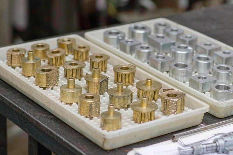 Machined brass and aluminum parts sorted into two inspection trays