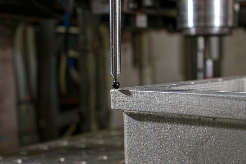 CMM probe touching the machined face of an aluminum housing on a granite table