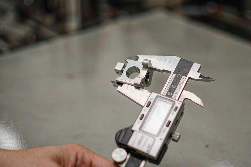 Digital caliper jaws measuring the outside diameter of a machined aluminum part