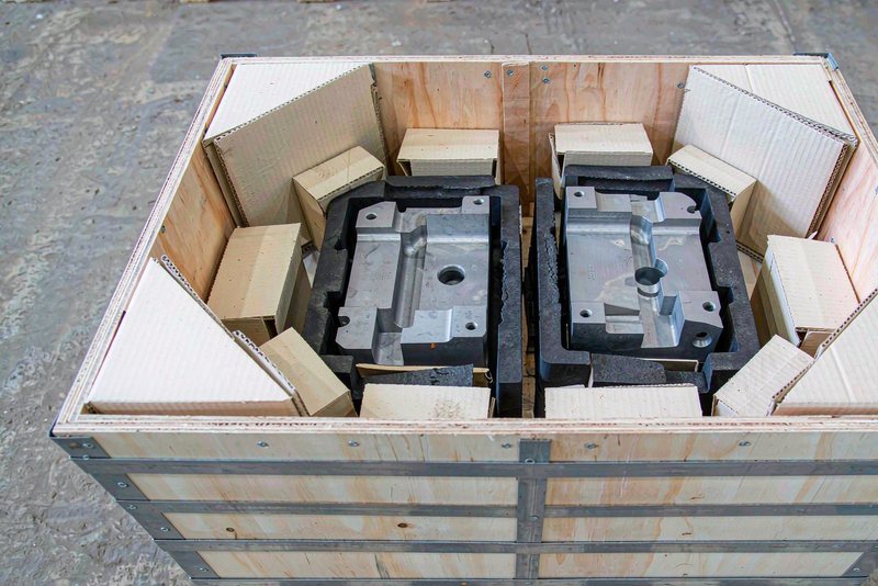Open wooden export crate with machined parts held in foam and corner protectors