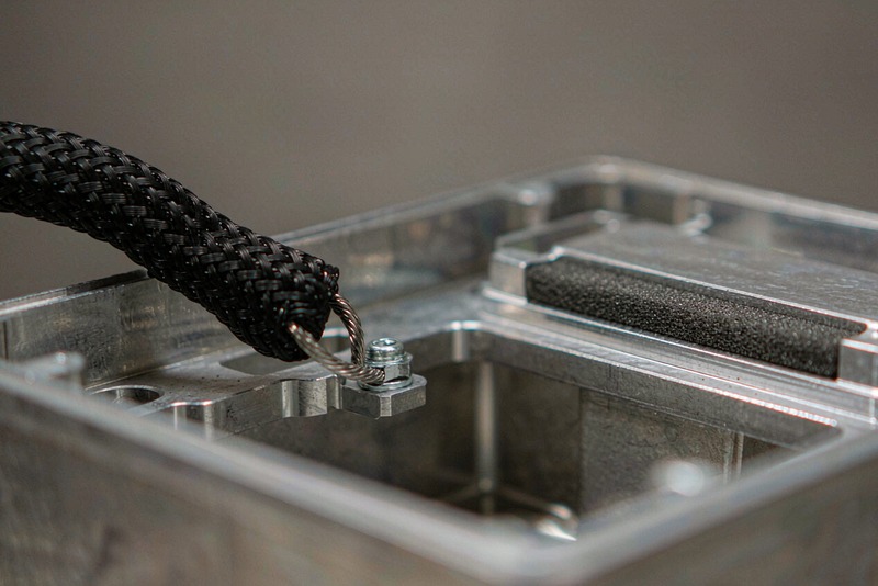Aluminum enclosure with a braided grounding strap bolted to a bare machined stud inside the wall