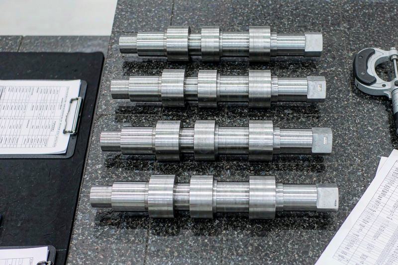 Stepped steel shafts in a row on a granite surface plate with a micrometer