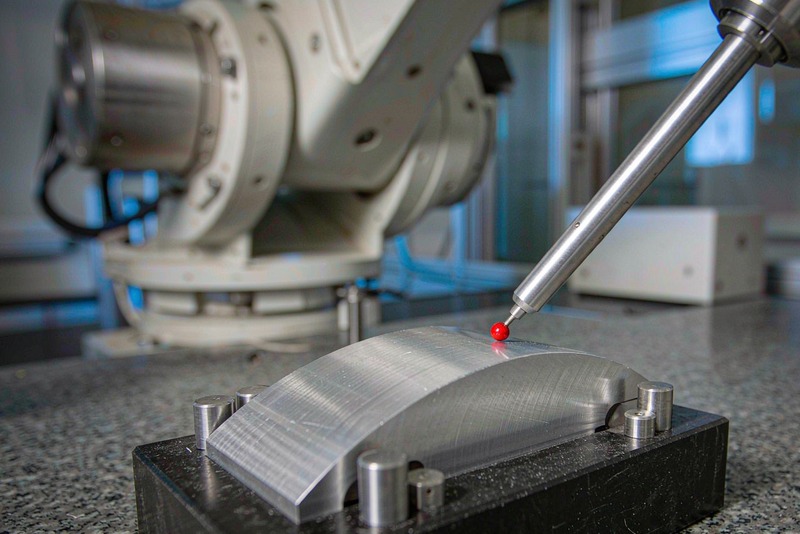 CMM ruby probe touching the contoured surface of a clamped aluminum part