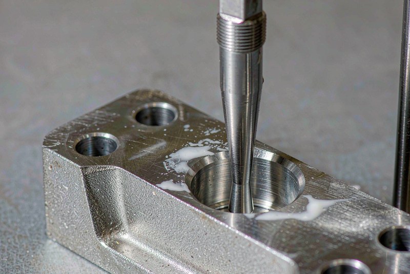 Steel plug gauge seated in a bored hole on an aluminum bracket