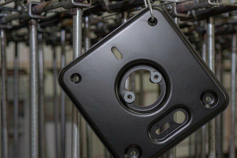 Powder coated machined aluminum bracket hanging on a coating line rack