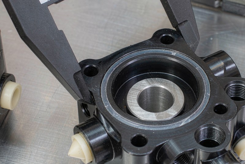 Black anodized aluminum housing with silicone plugs masking threaded ports