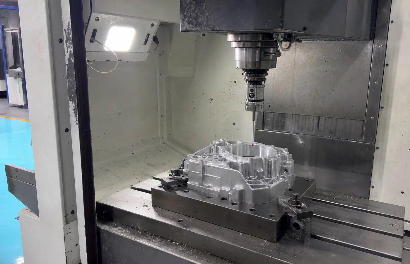 In-machine touch probe checking a machined aluminum housing inside a CNC machining center